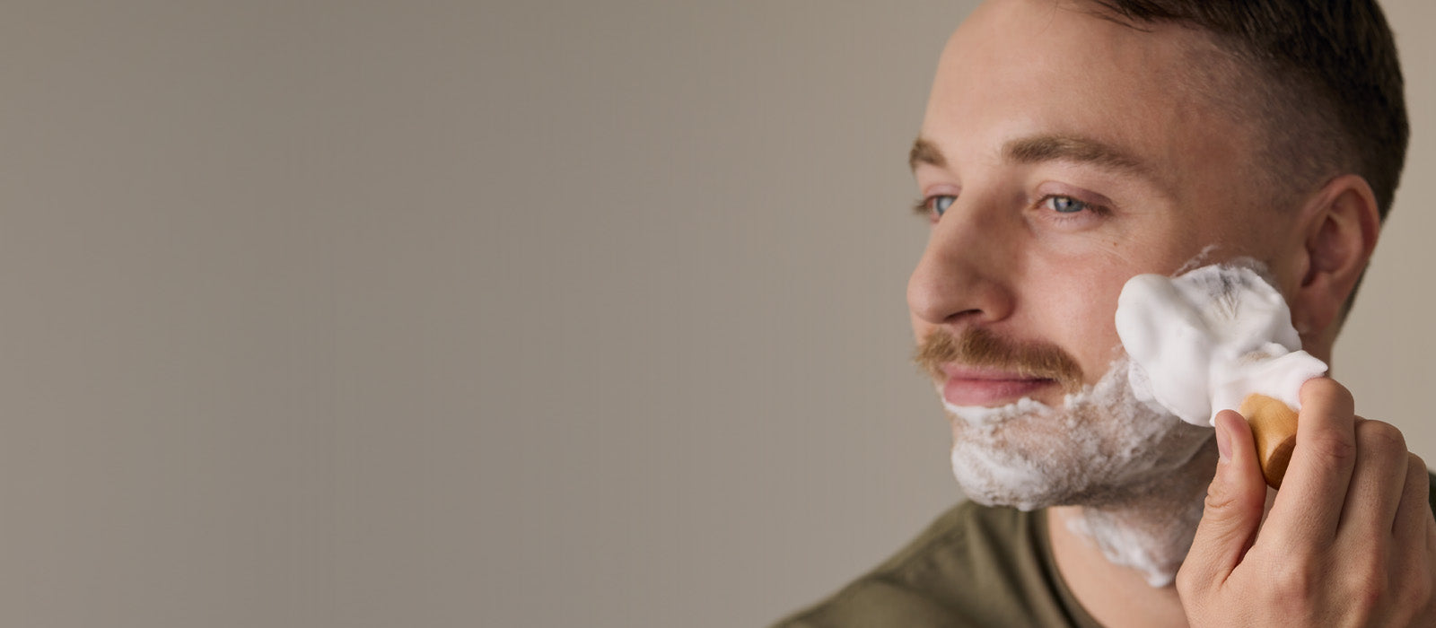 Man applies shave soap to his beard