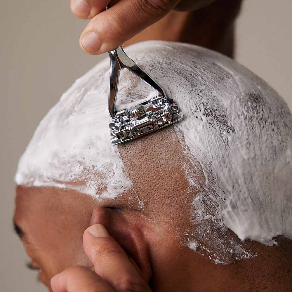 Man shaves behind his ear with the leaf razor