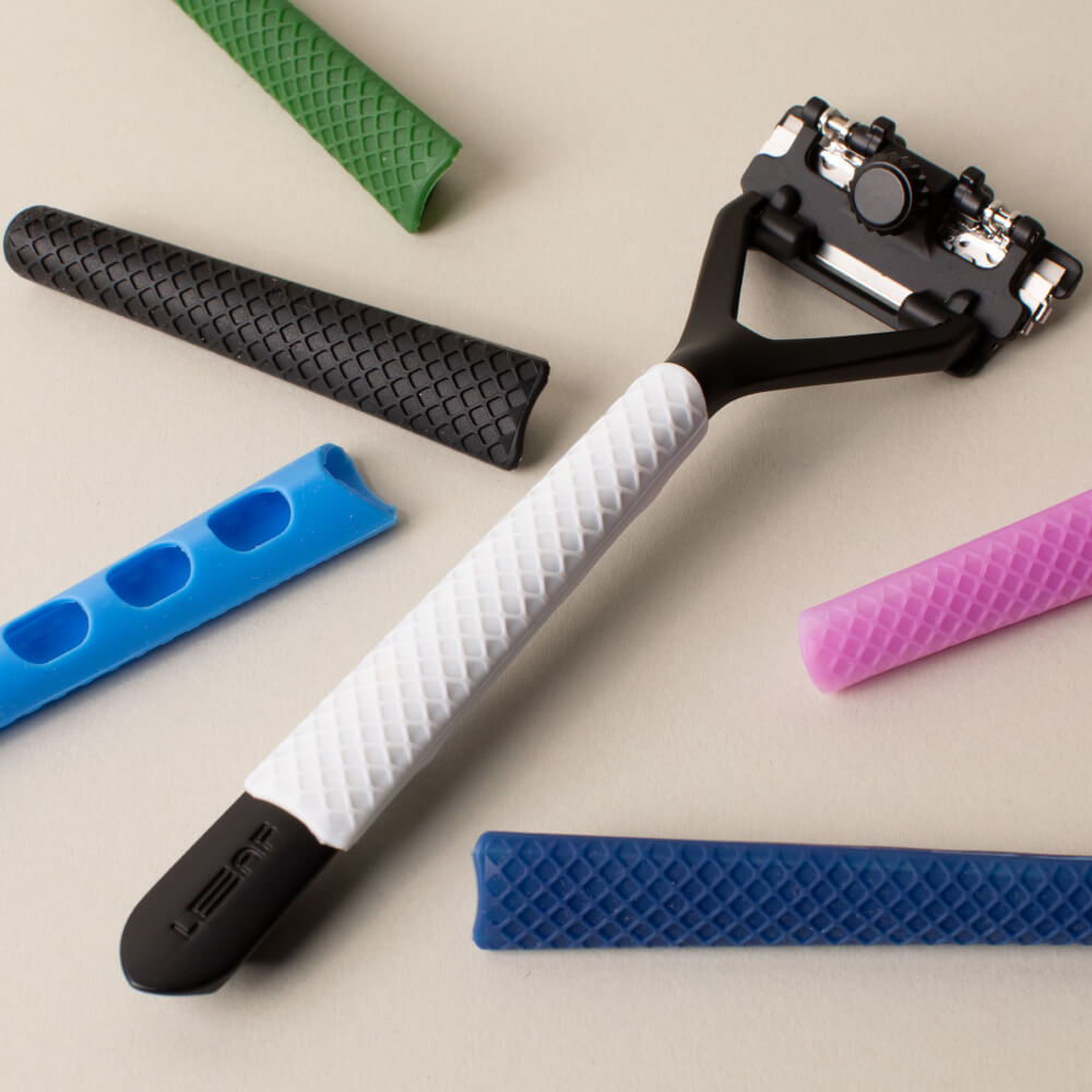 An assortment of the grip sleeves in multiple colors with the white sleeve on a razor