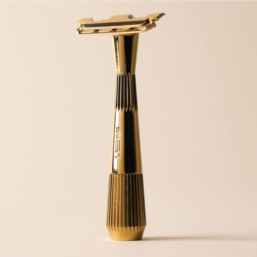 Gold single edge razor standing by itself