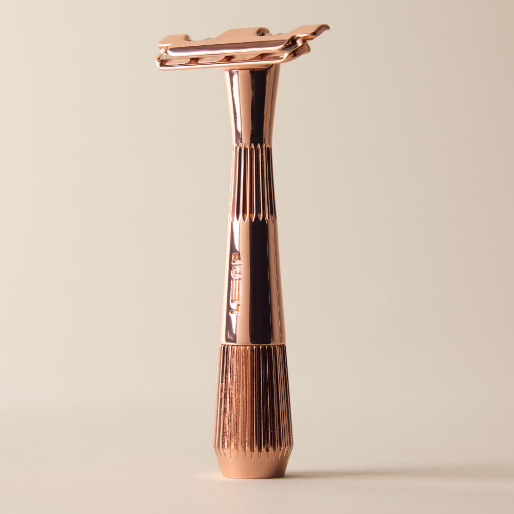 Rose gold single edge razor standing by itself